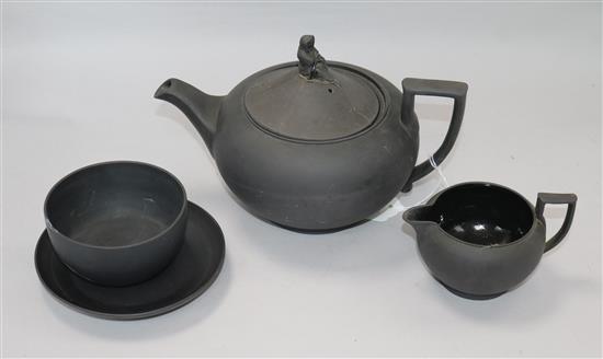 A black basalt teapot, a cream jug, a saucer and a bowl
